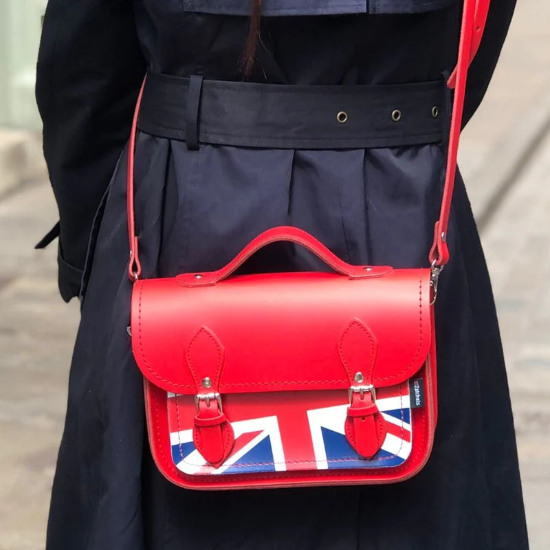 A woman wearing a midi satchel bag, in red, featuring the Union Jack on the front pocket