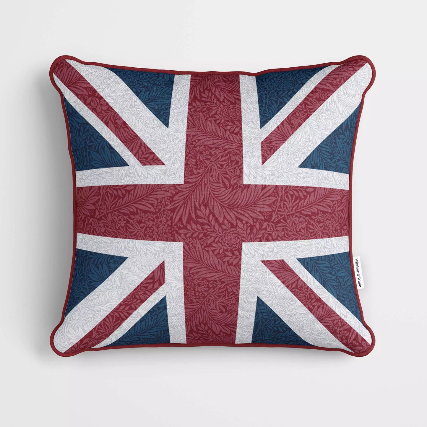 A cushion featuring the Union Jack on a William Morris Larkspur pattern velvet fabric, with red piping around the edge.