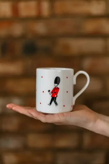 A mug with an illustration of a Queen's Guard over a hand palm